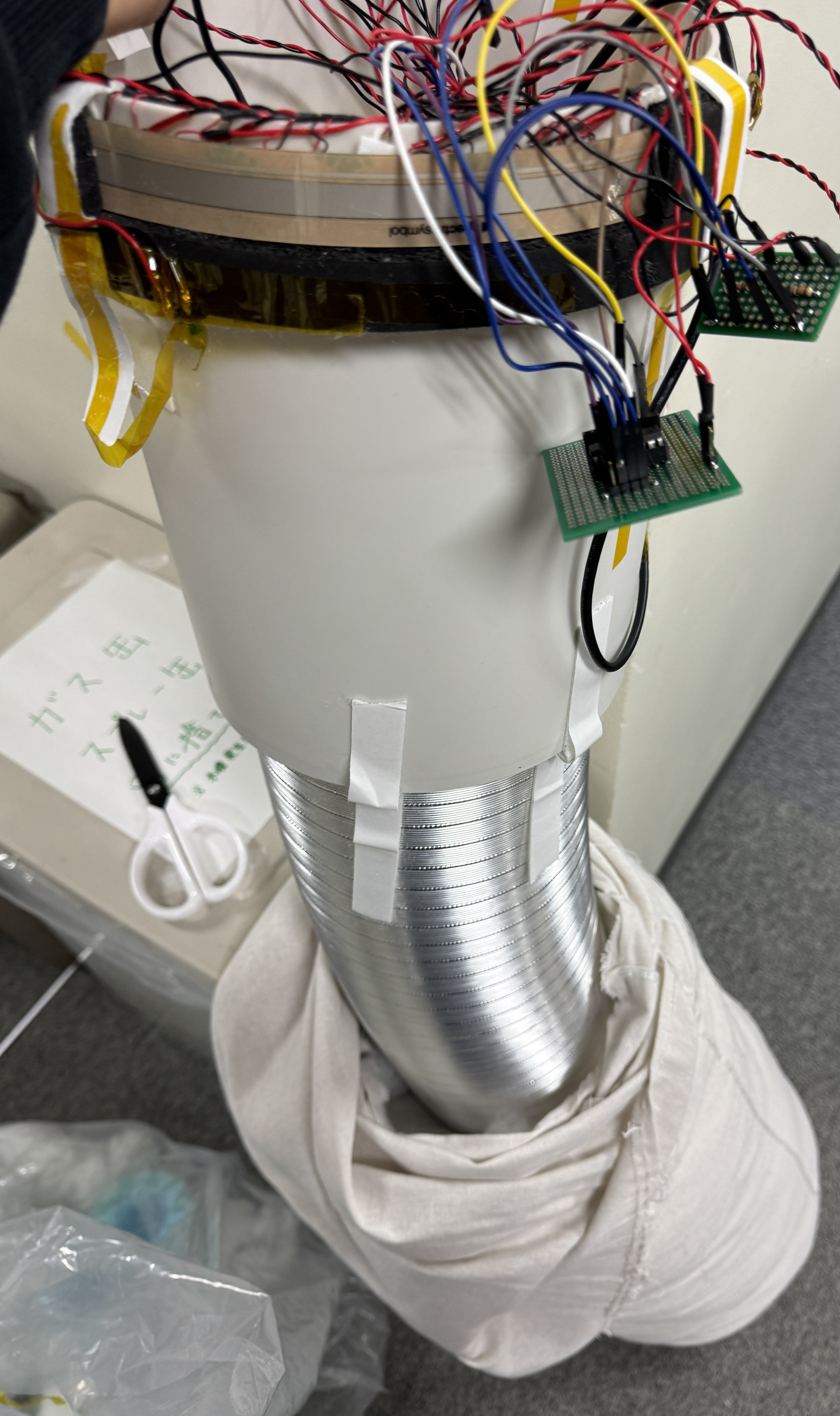 Inside the musical pillow, showing its supporting structure, circuit boards, and wiring beneath the fabric cover
